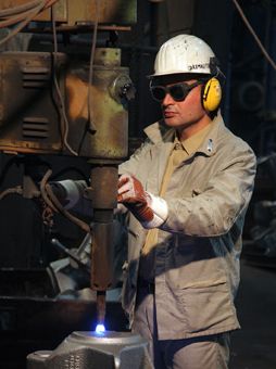 Arbeiter, der einen Helm mit Gehörschutz, eine Schutzbrille und Handschuhe trägt 